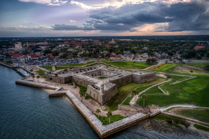 Aerial view of Castillo de San Marcos on the Matanzas River at dusk, with downtown St. Augustine spread out behind it